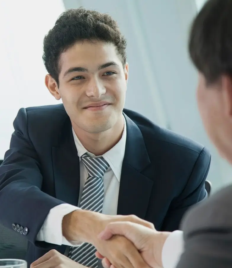 A man in suit shaking hands with another person.